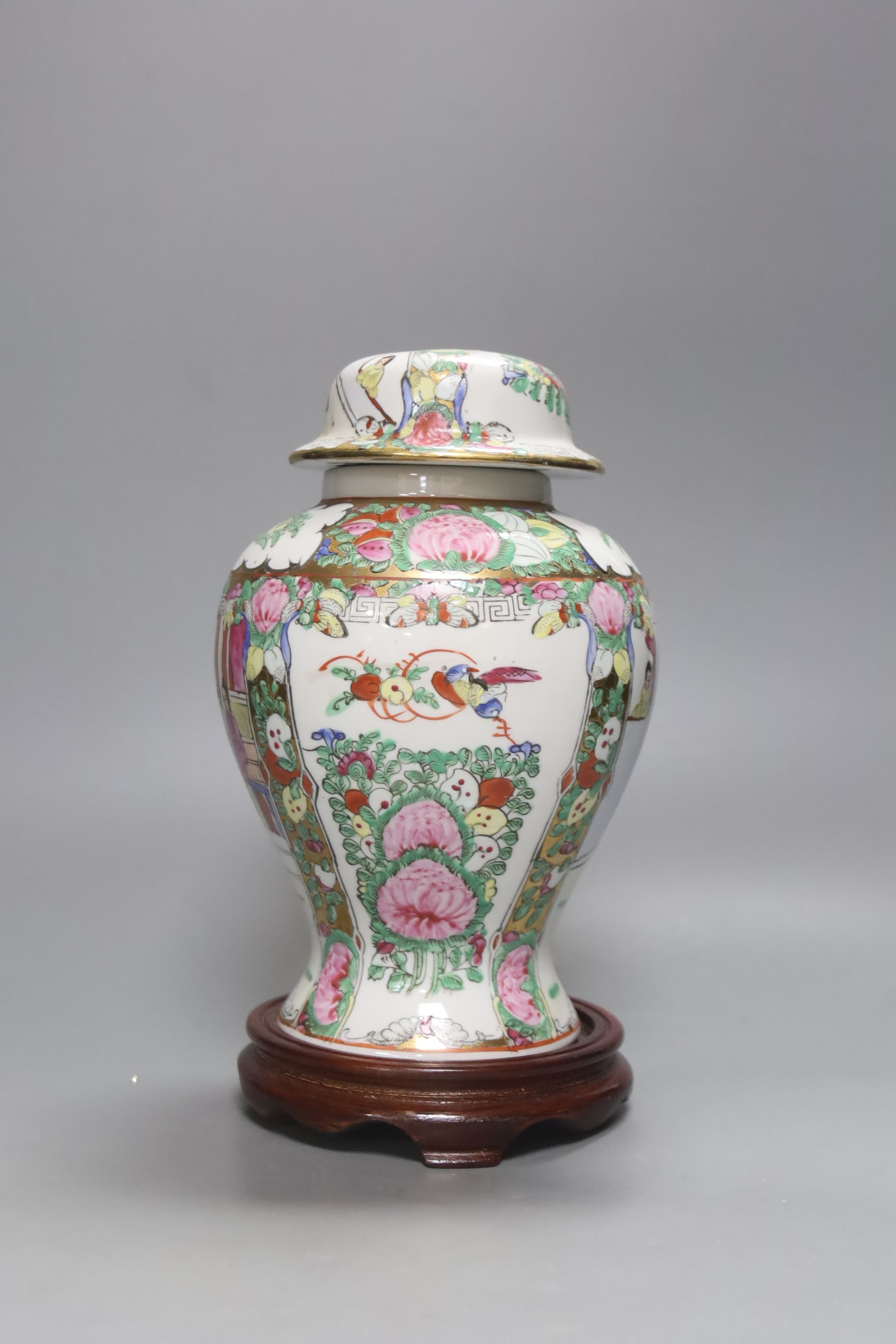 A Chinese famille rose urn shaped vase and lid, on wood plinth, 25cm